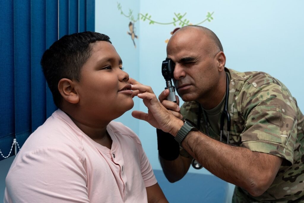 Miopia infantil: sinais, mitos e cuidados com a visão das crianças U.S. Air Force Lt. Col. Niyasdeen Dieguez, 482nd Medical Squadron pediatrician, performs an eye exam on a child during a community health event in San